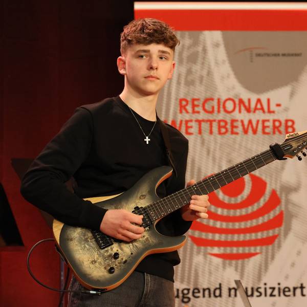 Lennart mit seiner Gitarre auf der Bühne des Regionalwettbewerbs.