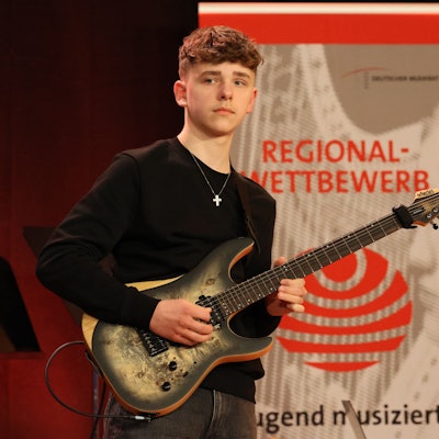 Lennart mit seiner Gitarre auf der Bühne des Regionalwettbewerbs.