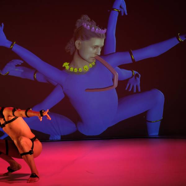 Ein Tänzer aus Singapur in Lederriemen tanzt vor einer Videoinstallation, die eine singapurische Gottheit persifliert.