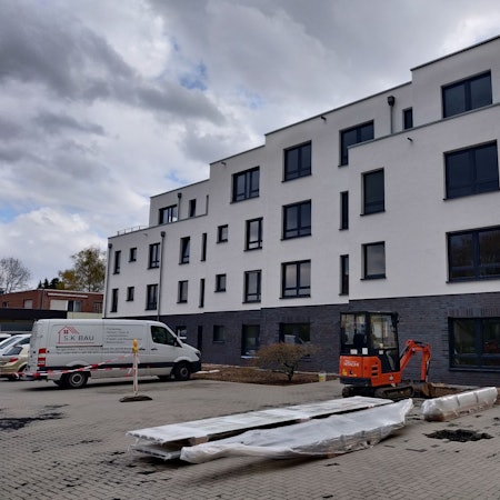 Ein Neubau. Im Vordergrund ist ein kleiner Bagger und der Lieferwagen einer Baufirma zu sehen.