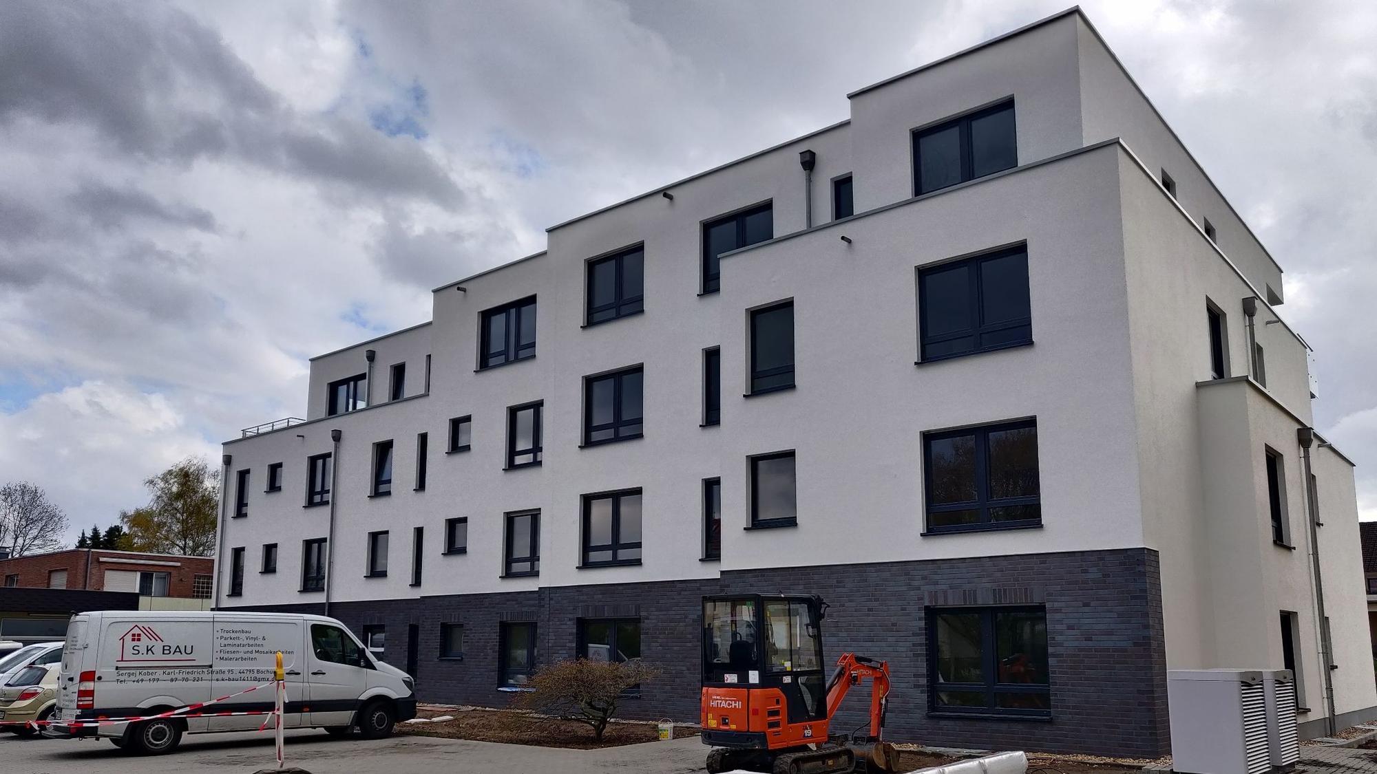 Ein Neubau. Im Vordergrund ist ein kleiner Bagger und der Lieferwagen einer Baufirma zu sehen.