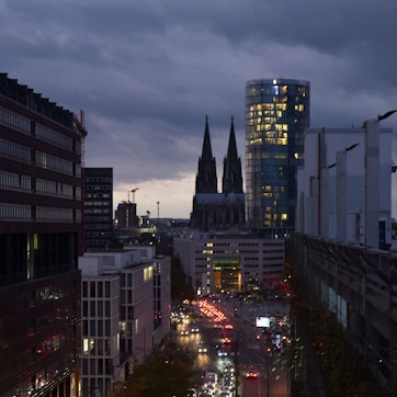 Blick auf den Kölner Dom mit bewölktem herbstlichem Abendhimmel als Hintergrund vom Deutzer Stadthaus aus fotografiert. Rechts im Bild: das Hochhaus Köln-Triangel, in dem die Metropolregion Rheinland ihren Sitz hat.