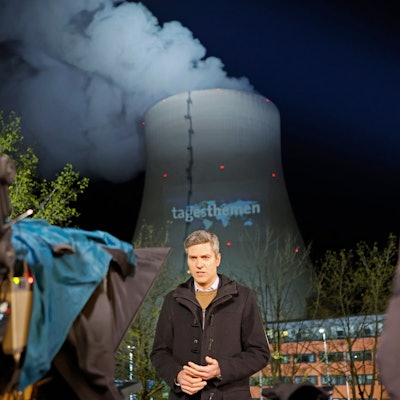 „Tagesthemen“-Moderator Ingo Zamperoni steht auf einem Balkon vor dem Kühlturm des AKW Isar 2.