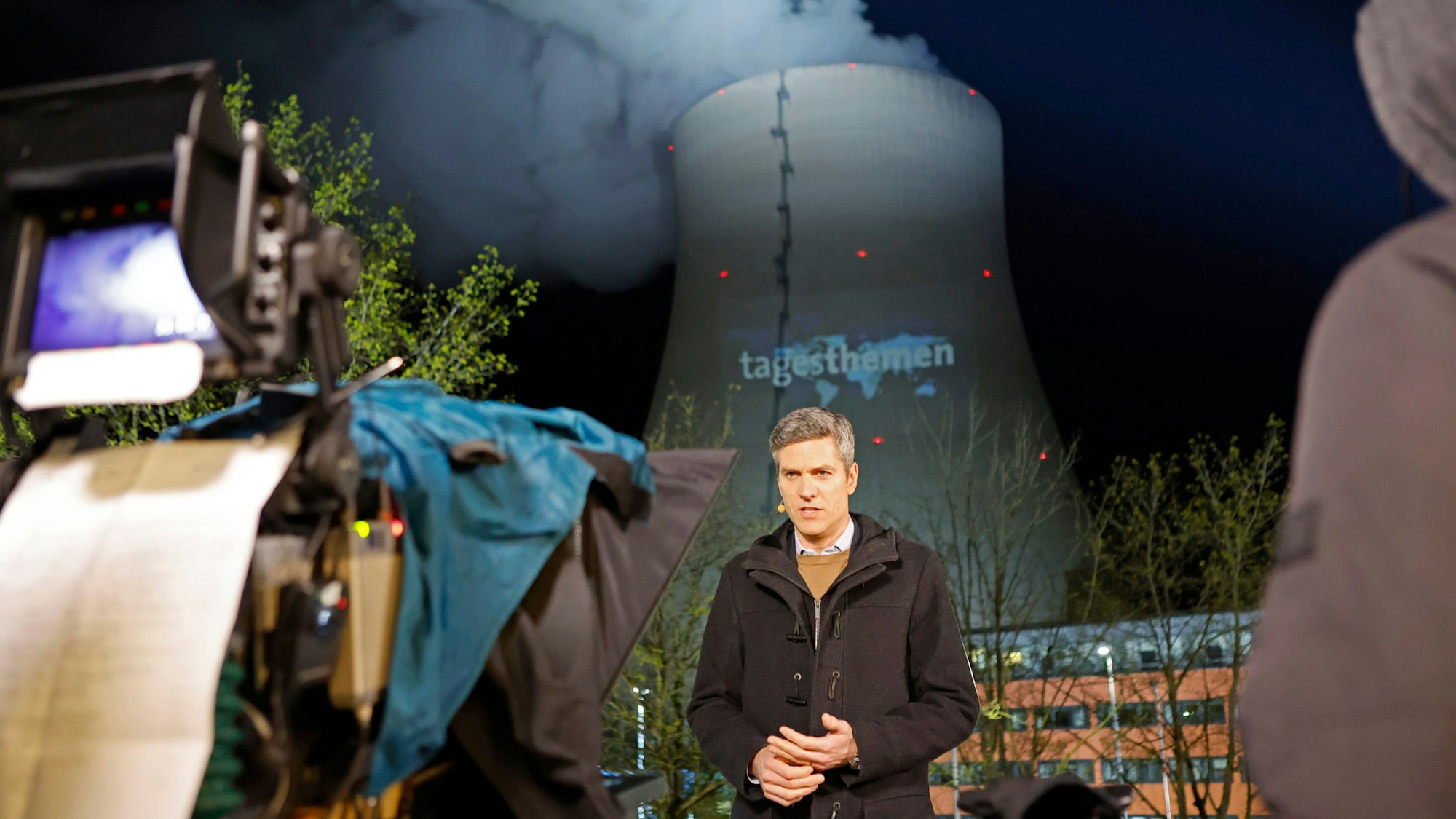 „Tagesthemen“-Moderator Ingo Zamperoni steht auf einem Balkon vor dem Kühlturm des AKW Isar 2.
