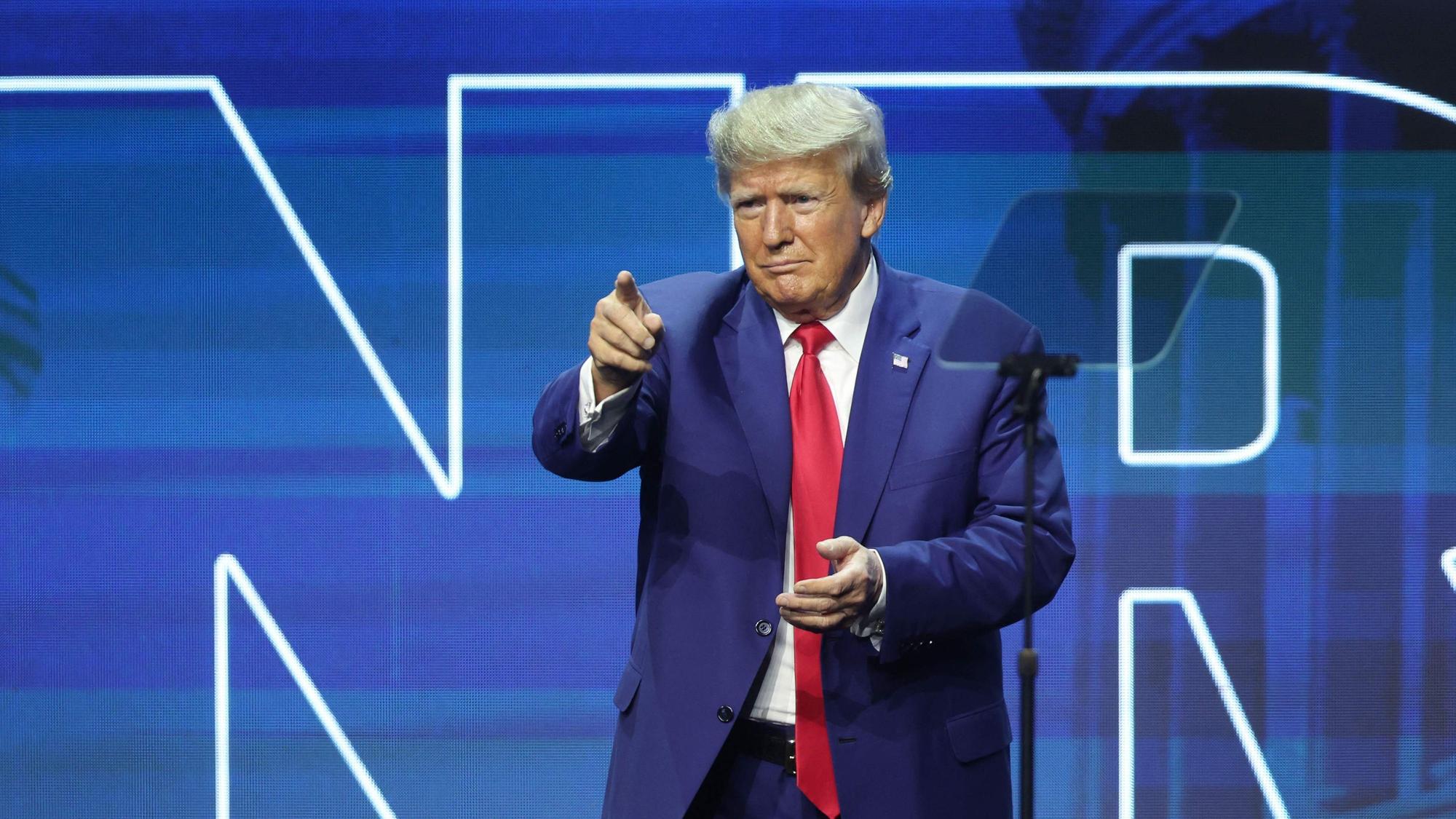Es ist Donald Trump auf einer Bühne zu sehen. Er zeigt mit seinem Finger ins Publikum.