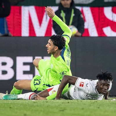 Leverkusens Odilon Kossounou (r,) im Zweikampf gegen Wolfsburgs Omar Marmoush.