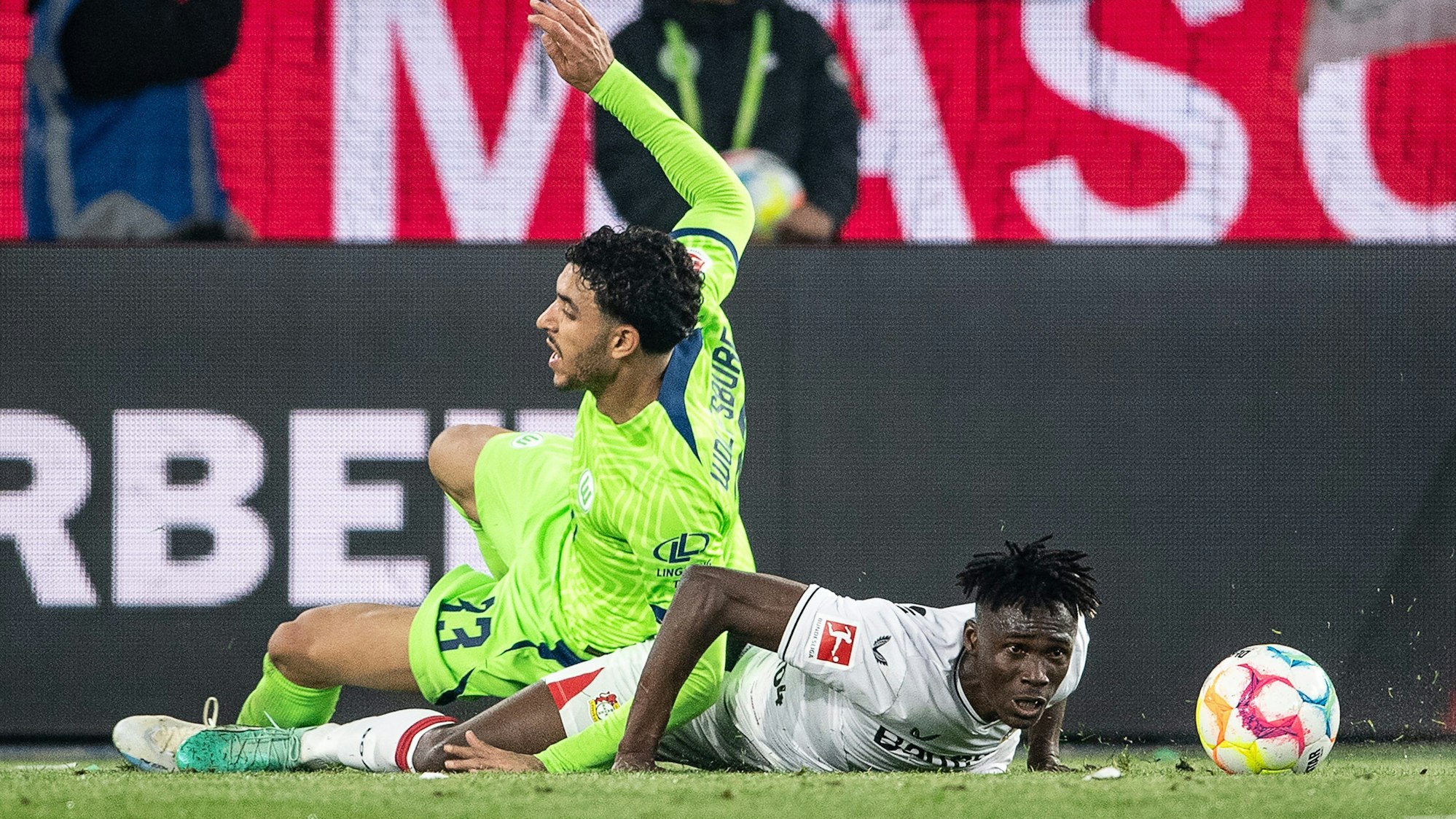 Leverkusens Odilon Kossounou (r,) im Zweikampf gegen Wolfsburgs Omar Marmoush.