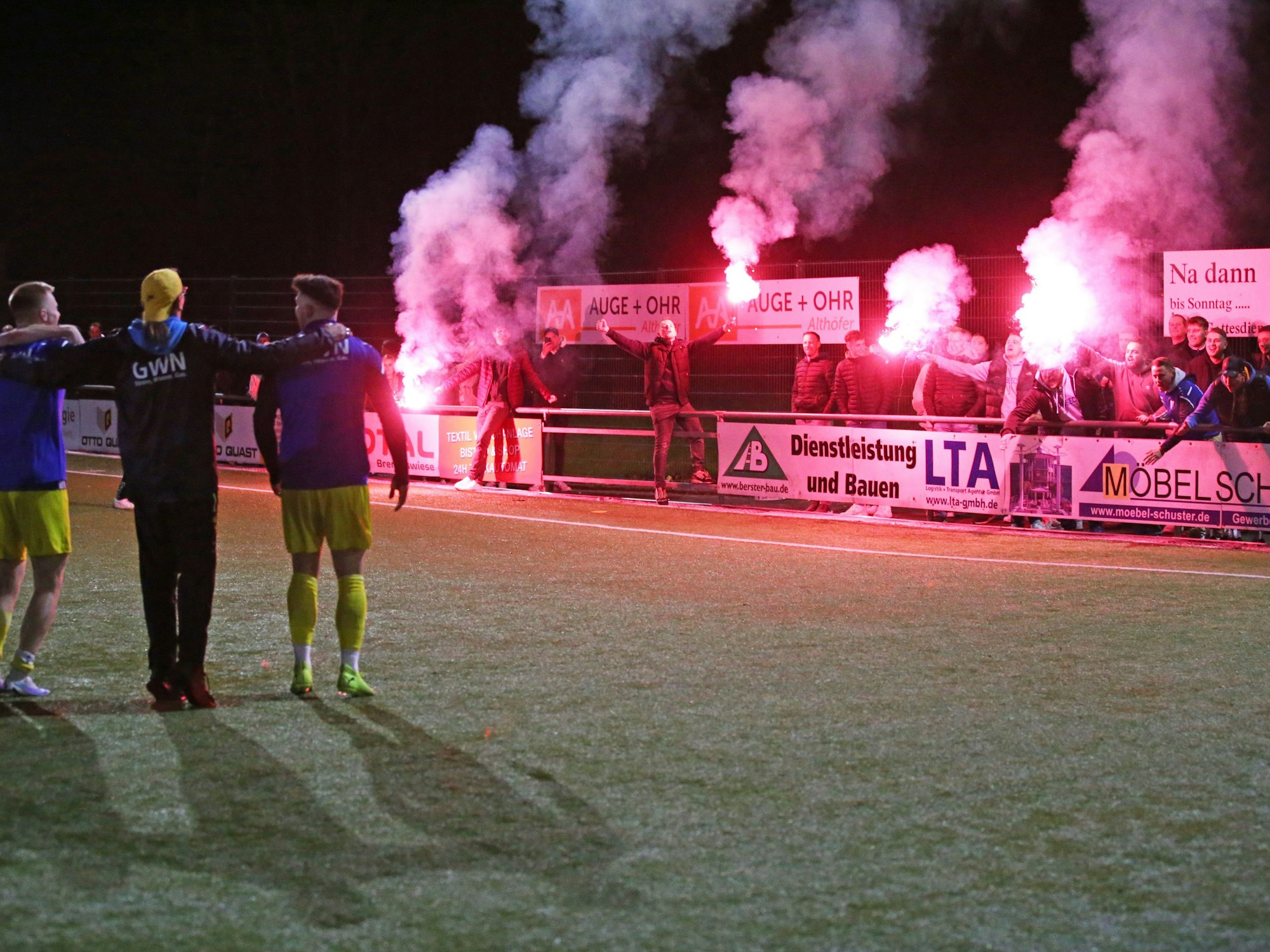 Zu sehen sind Fußballfans, die auf einem Fußballplatz Pyrotechnik abbrennen.