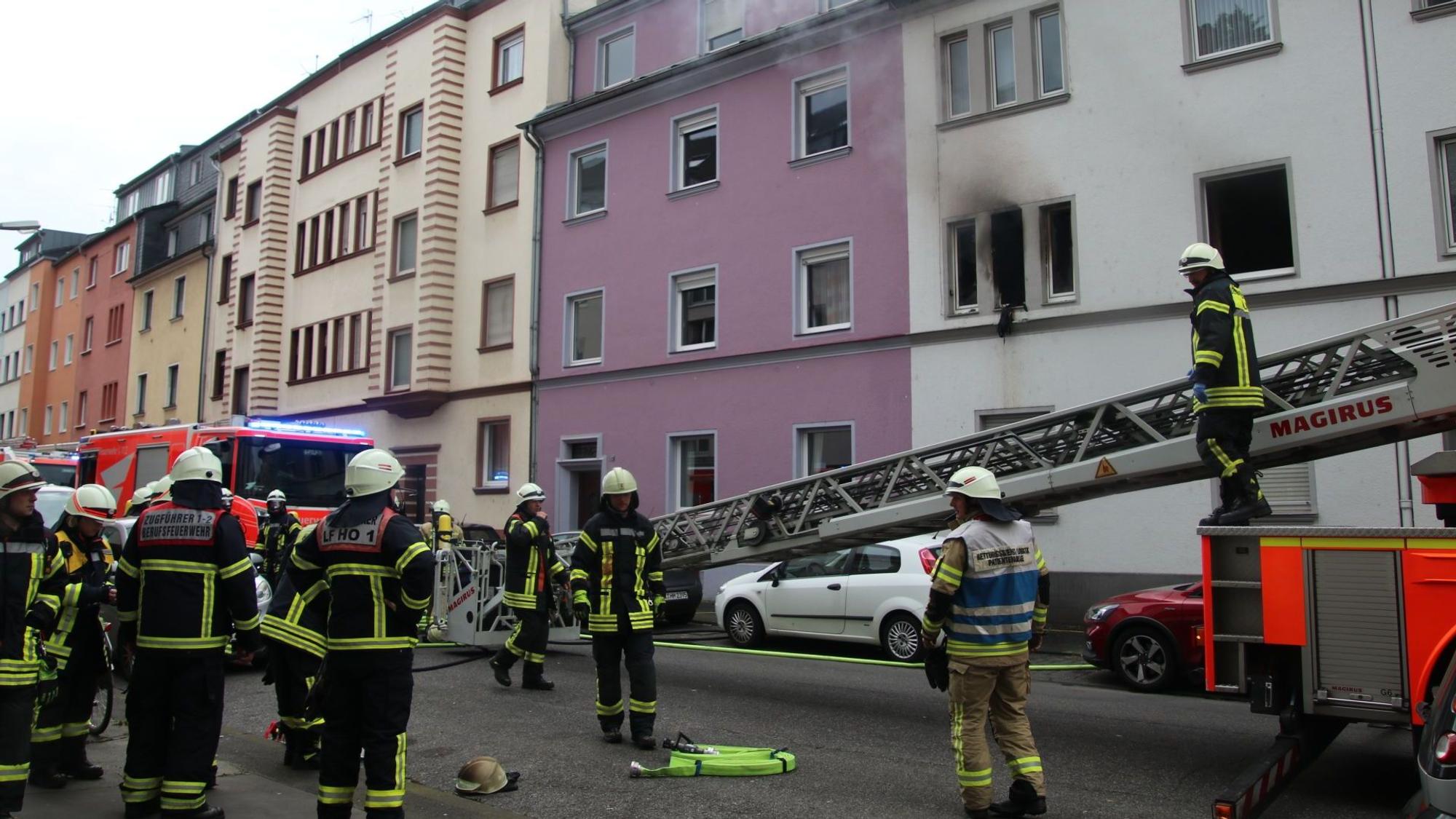 Feuerwehrleute stehen vor einem rußgeschwärzten Fenster in der Kniprodestraße.