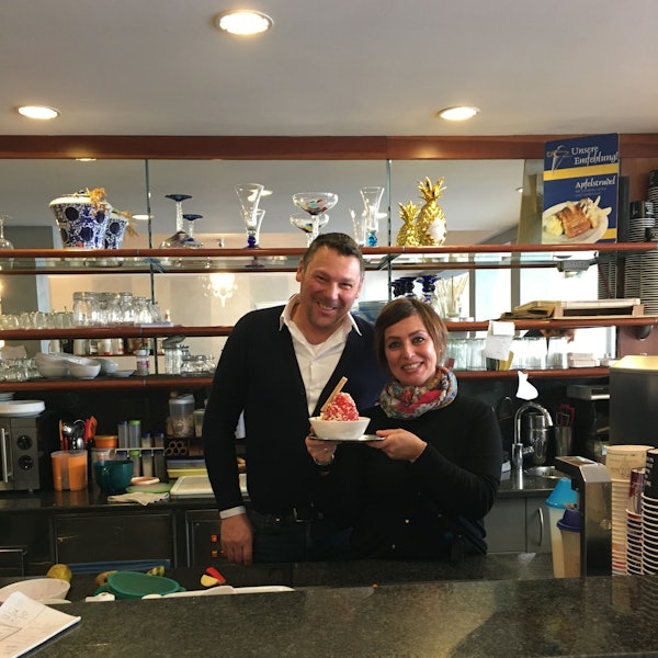 Ein Ehepaar, das eine Eisdiele betreibt, hält in ihrer Mitte ein Spaghetti-Eis.