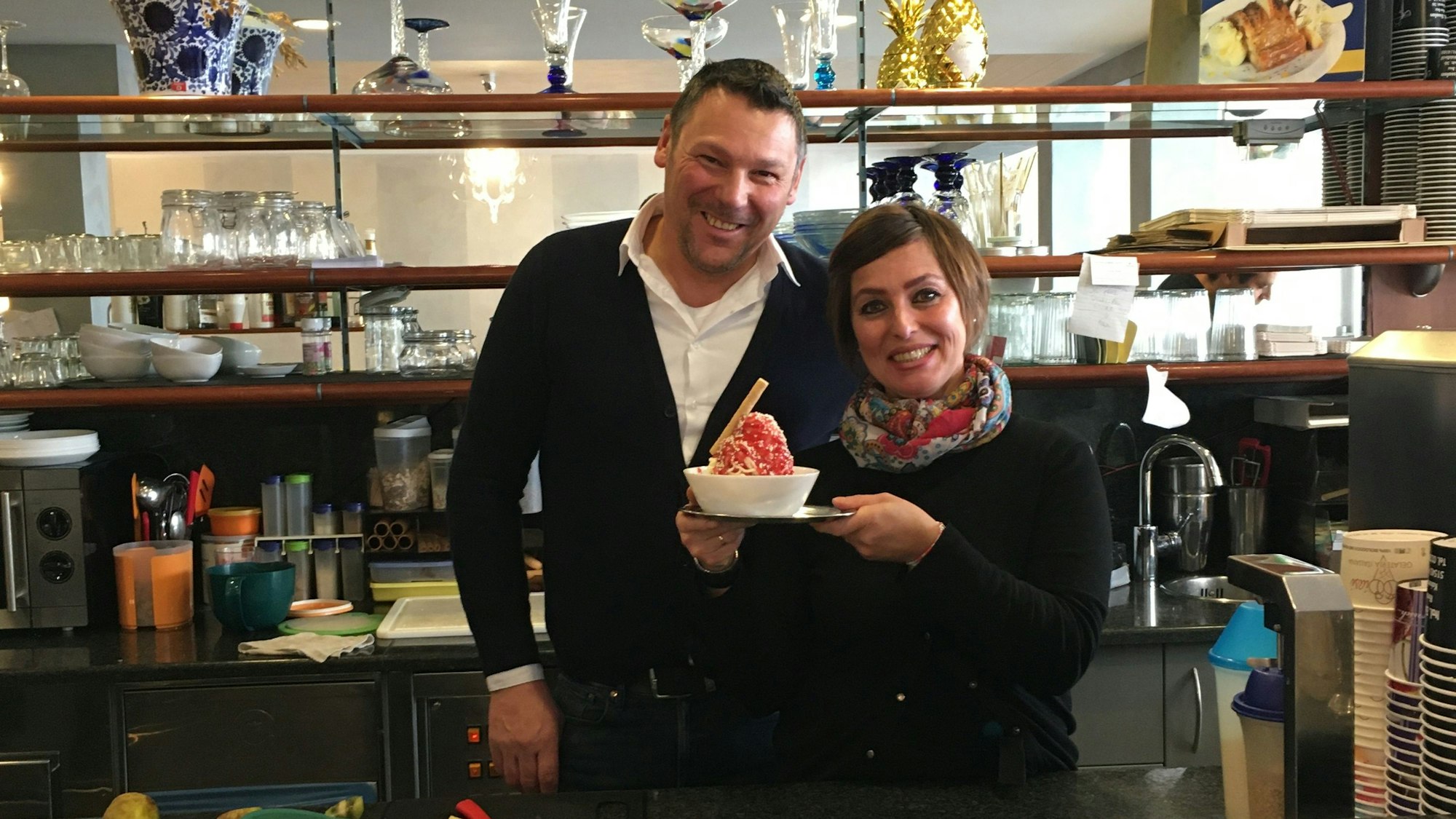 Ein Ehepaar, das eine Eisdiele betreibt, hält in ihrer Mitte ein Spaghetti-Eis.