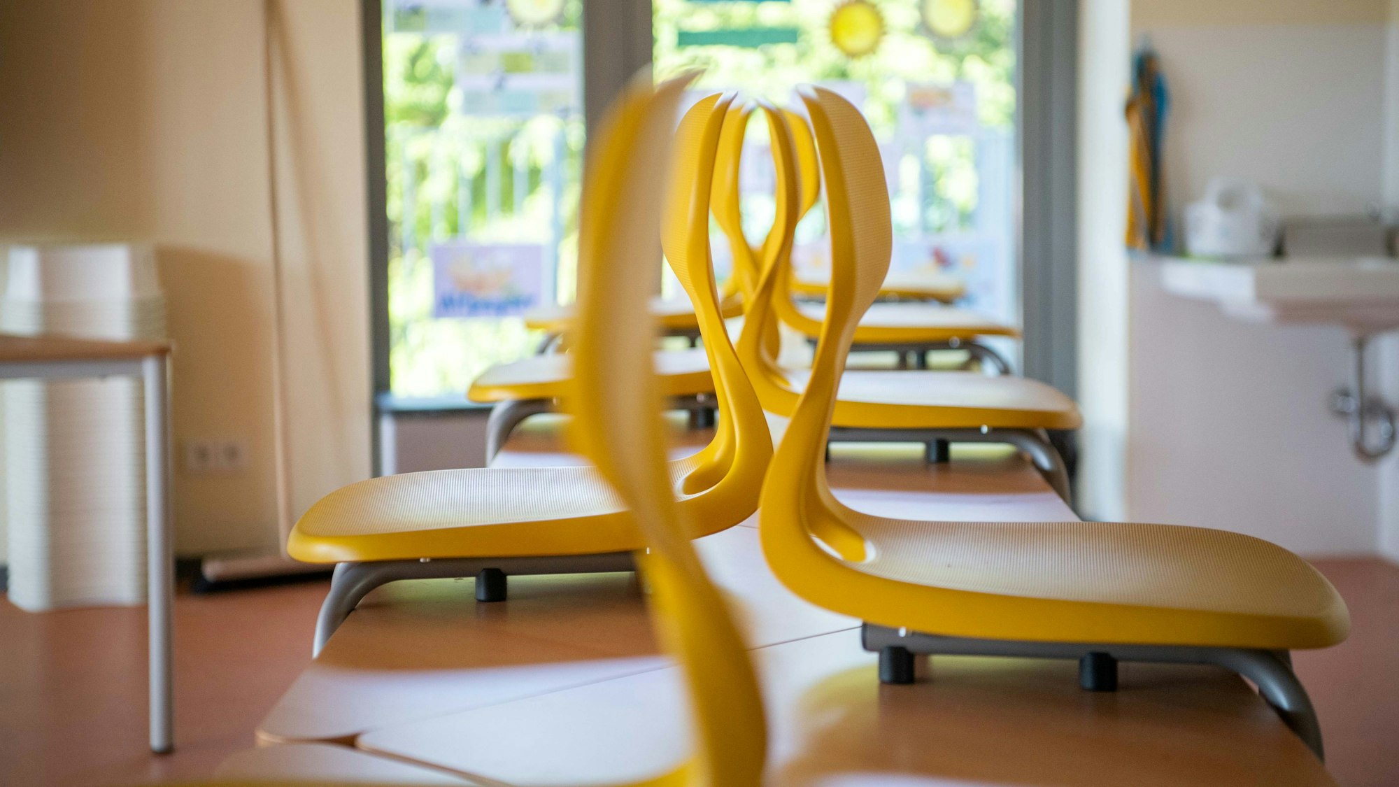 Gelbe Stühle sind im menschenleeren Klassenraum auf die Pulte gestellt worden.