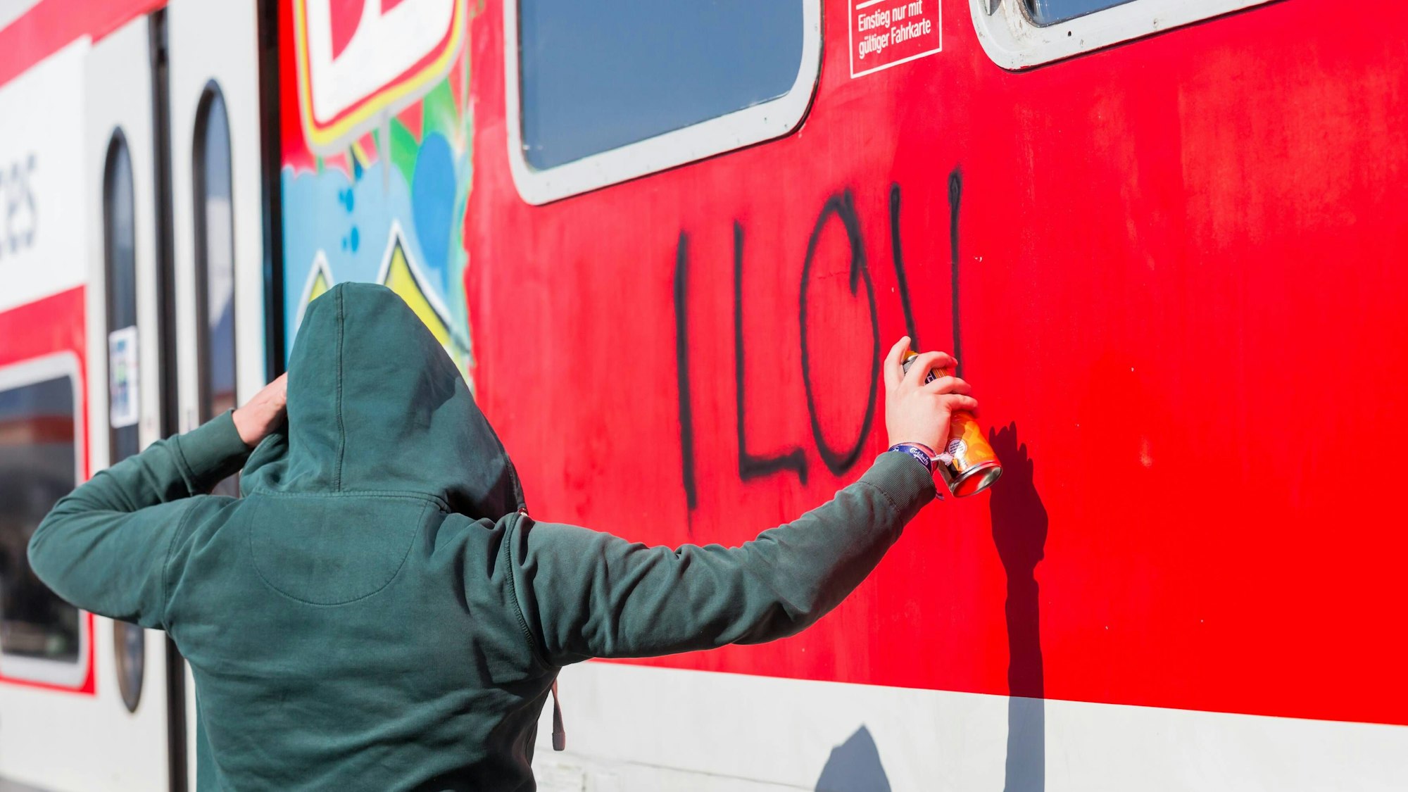 Ein Sprayer besprüht illegal einen Zug.