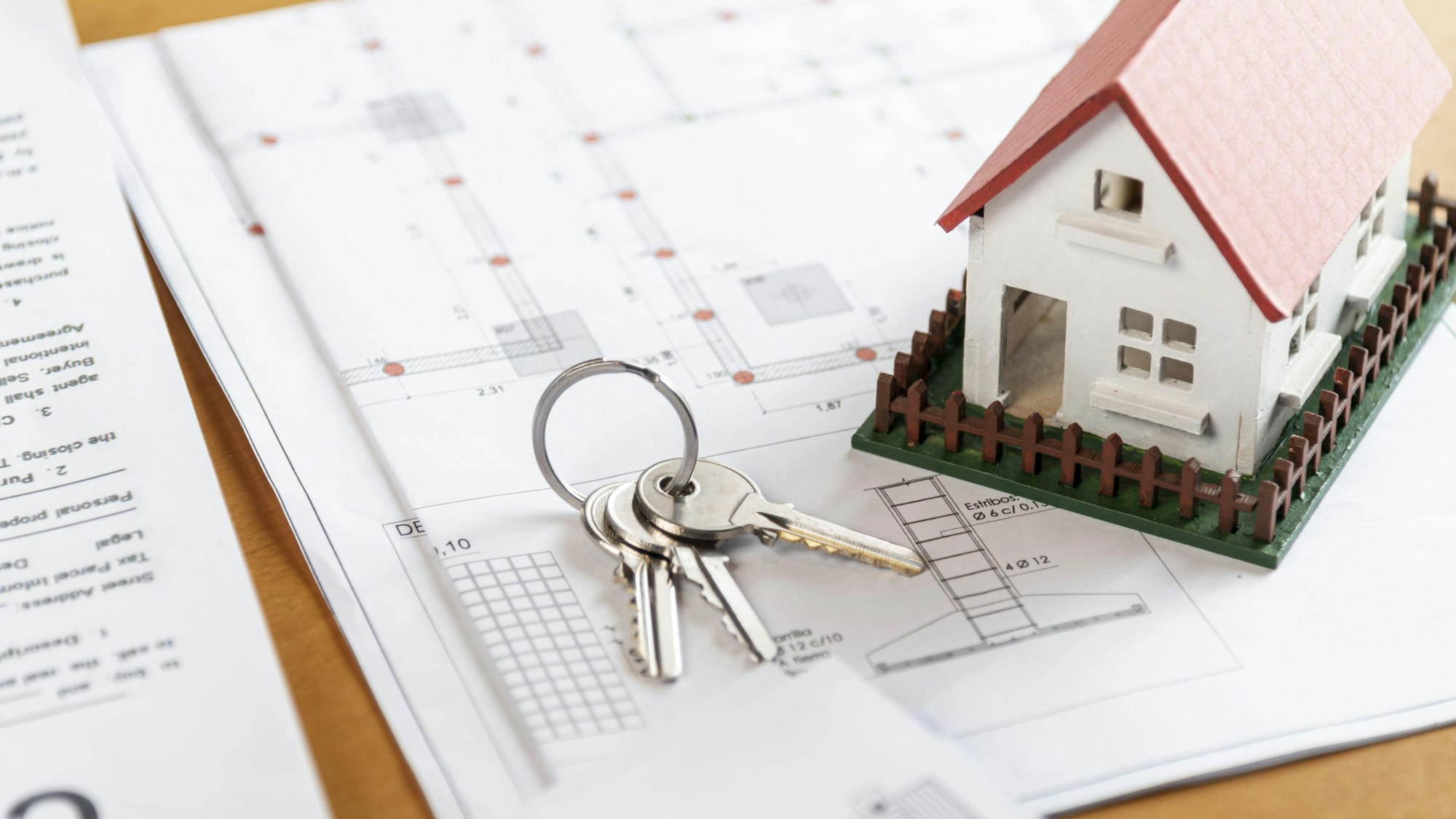 Spielzeughaus und ein Schlüssel liegen auf Plänen eines Hauses.