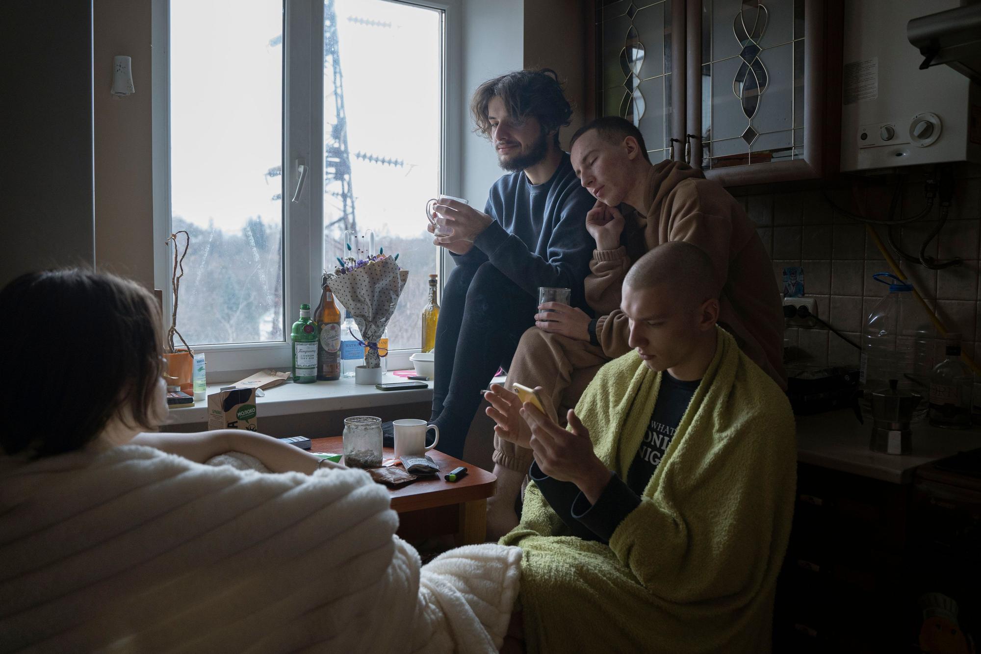 Sasha N. und sein Freund Roman leben in einer WG. Wegen der russischen Angriffe auf die Energiesysteme fallen die Heizungen aus, deshalb sitzen sie in Decken eingewickelt am Fenster.
