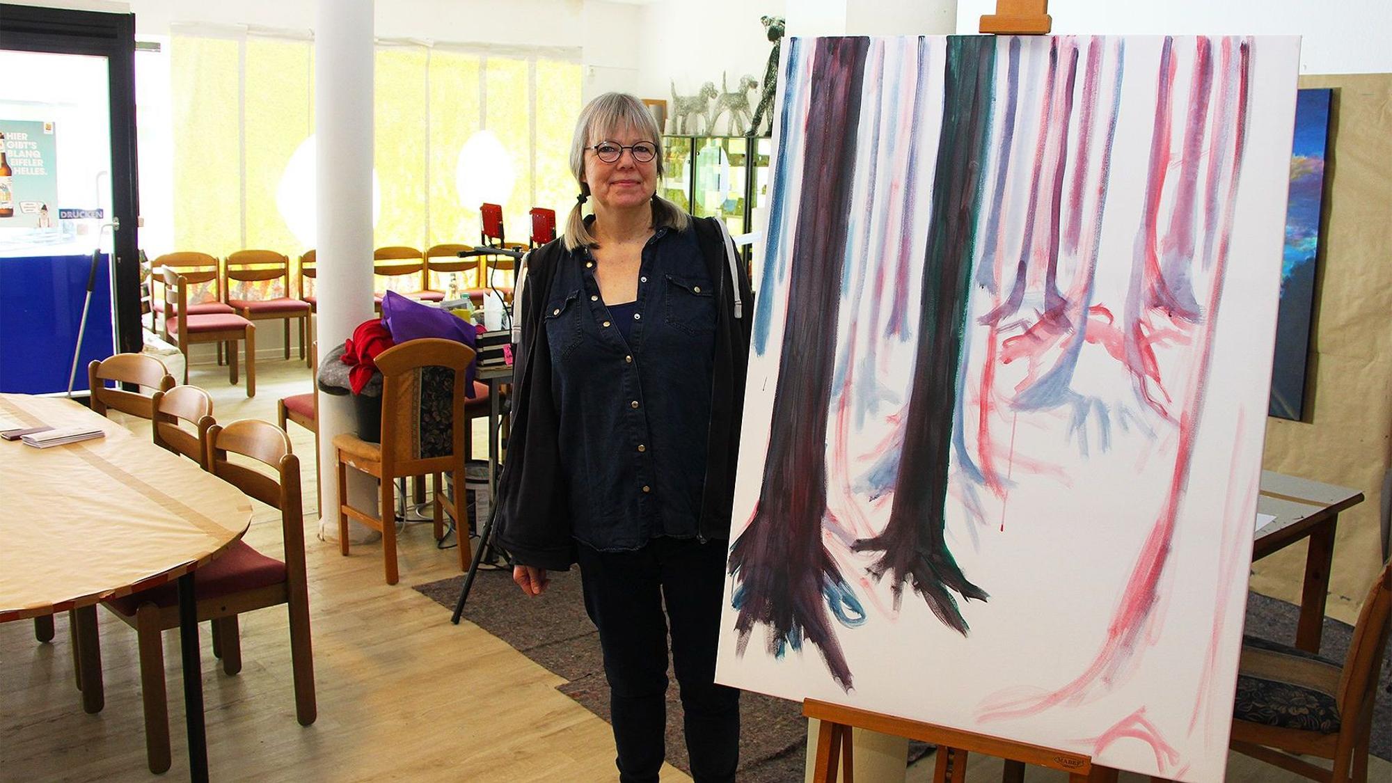 Eine Frau steht neben einem Kunstgemälde