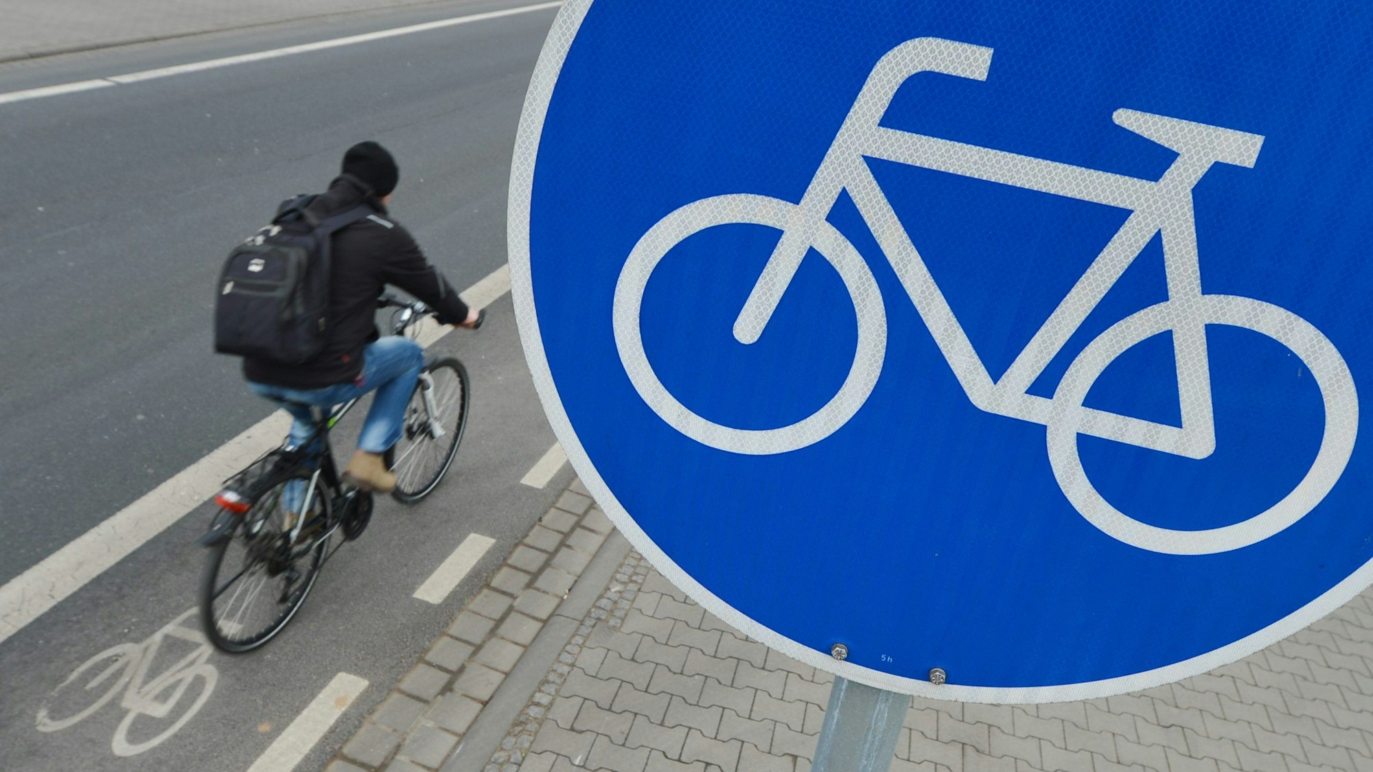 Ein Mann fährt mit seinem Fahrrad auf einem mit einem Verkehrsschild gekennzeichneten Radweg.