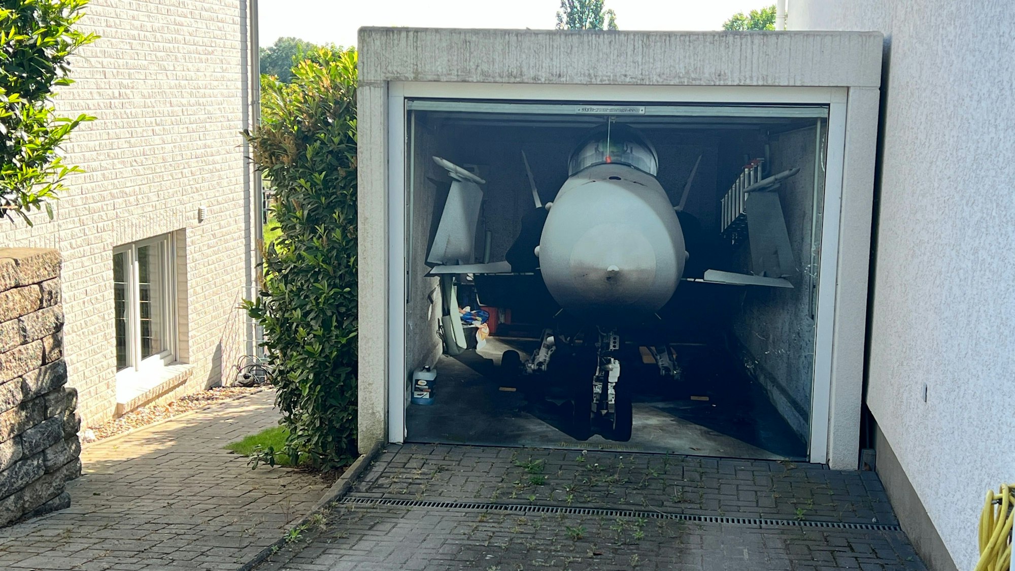 Fotorealistisch auf ein Garagentor aufgemalter Düsenjäger in Rheindorf
