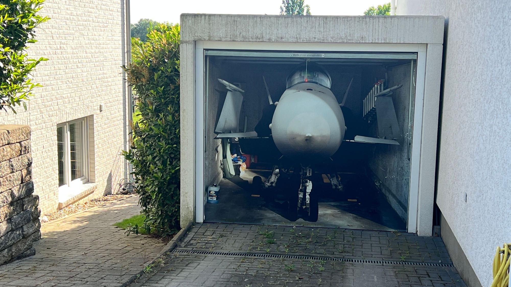 Fotorealistisch auf ein Garagentor aufgemalter Düsenjäger in Rheindorf