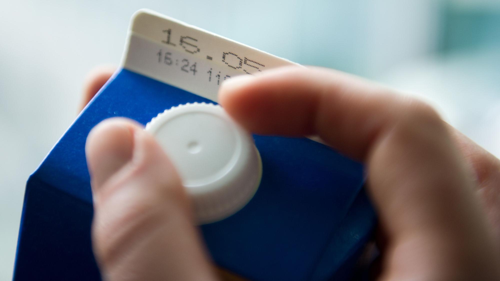 Eine Hand öffnet einen Tetrapack Milch mit dem Mindesthaltbarkeitsdatum «16.05.».