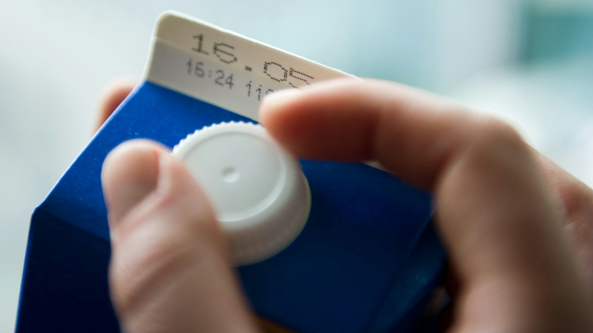 Eine Hand öffnet einen Tetrapack Milch mit dem Mindesthaltbarkeitsdatum «16.05.».