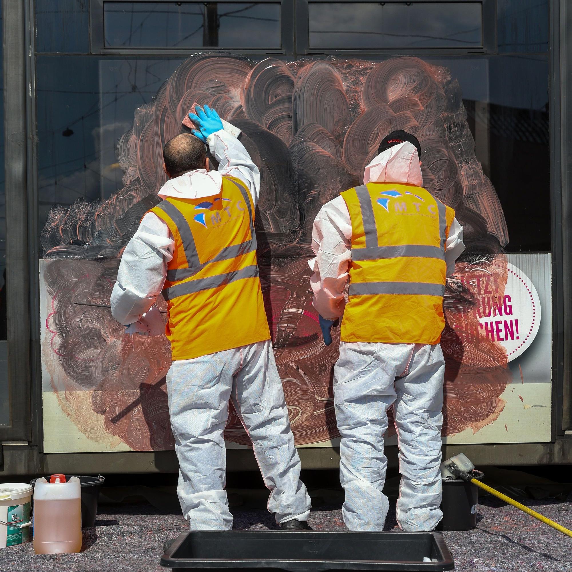 Arbeiter entfernen ein Graffiti von einer KVB-Bahn.