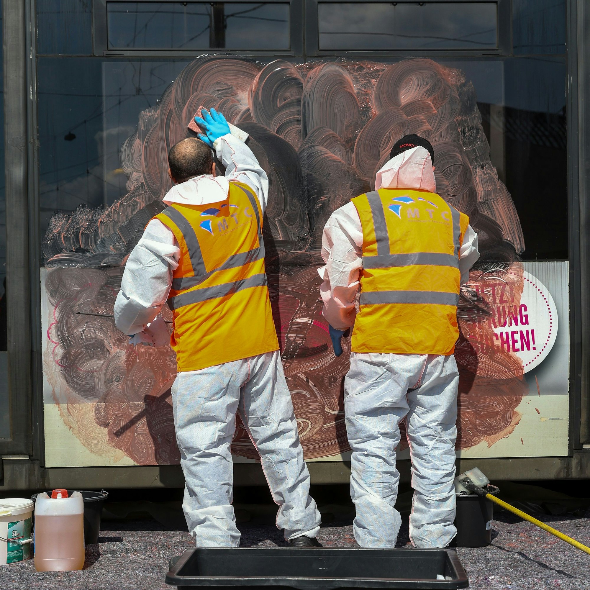 Arbeiter entfernen ein Graffiti von einer KVB-Bahn.