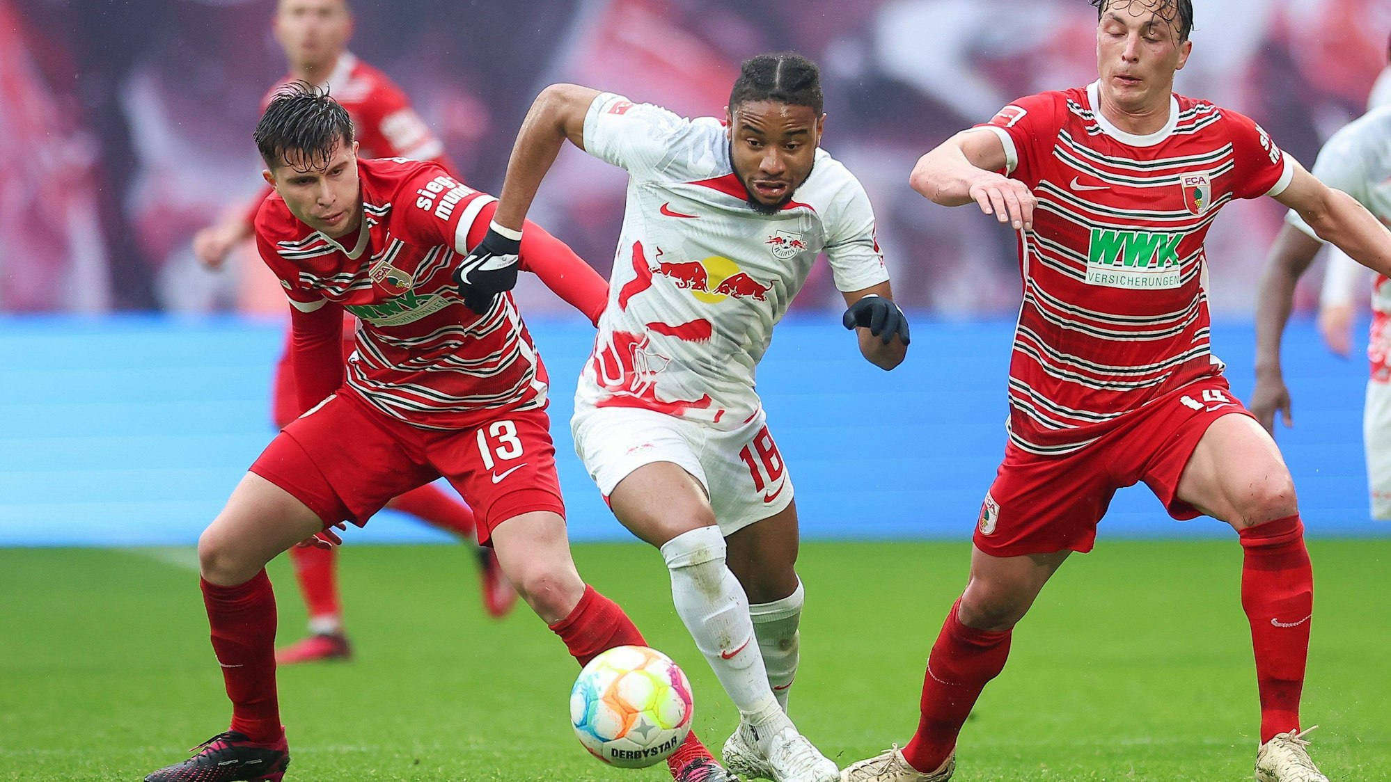 Leipzigs Spieler Christopher Nkunku und Augsburgs Elvis Rexhbecaj und Julian Baumgartlinger kämpfen um den Ball.