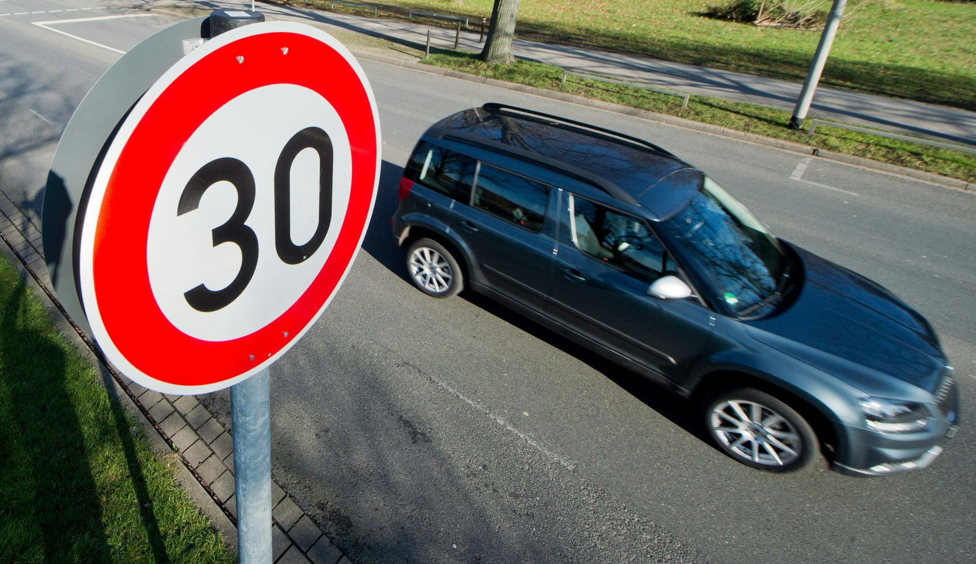 Ein Auto fährt an einem Verkehrsschild für eine Geschwindigkeitsbegrenzung von 30 Stundenkilometern vorbei.