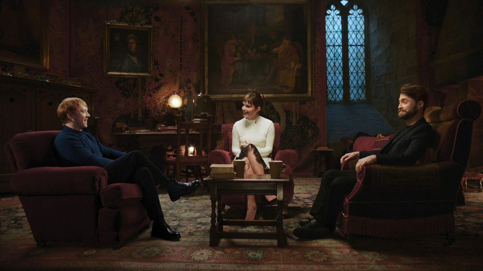 Rupert Grint, Emma Watson und Daniel Radcliffe in der HBO-Reunion-Show „Harry Potters 20. Geburtstag: Rückkehr nach Hogwarts“. Sie sitzen in einer gemütlichen Runde auf Sesseln und reden miteinander.