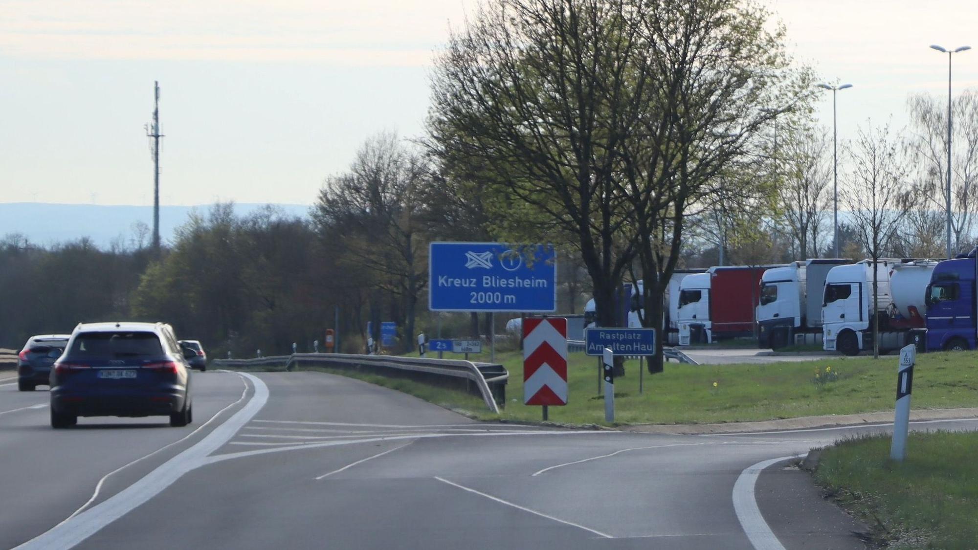 Auf dem Foto ist die Abfahrt zum Rastplatz „Am alten Hau“ zu sehen. Er ist ein beliebter Treffpunkt für Homosexuelle. Um ungestört zu sein, schneiden sie Zäune auf, durch die allerdings Wildschweine auf die Autobahn gelangen können.