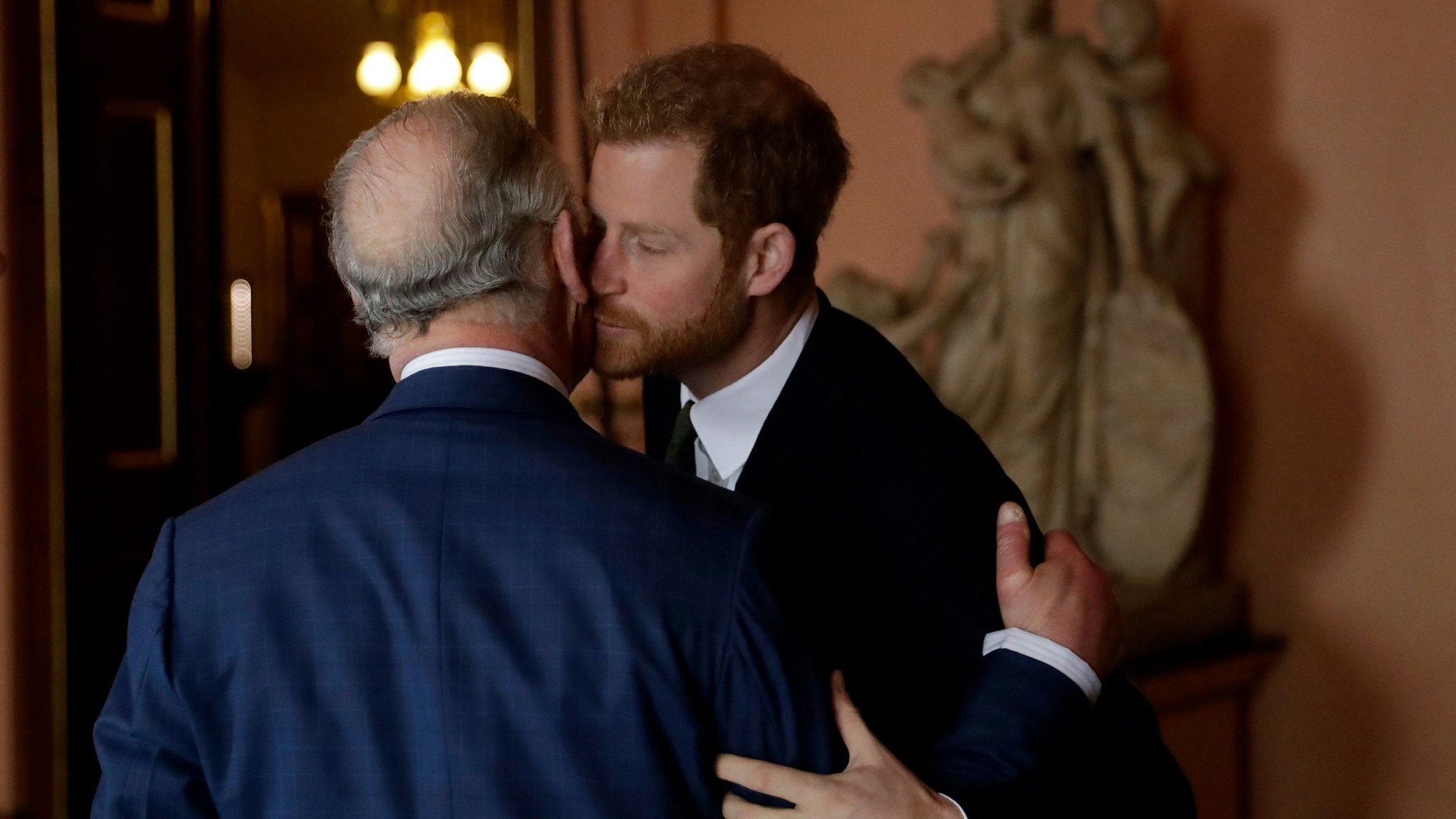 König Charles III. und sein Sohn, Prinz Harry, küssen sich auf die Wange.