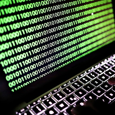 Auf dem Bildschirm eines Laptops ist ein Binärcode zu sehen.