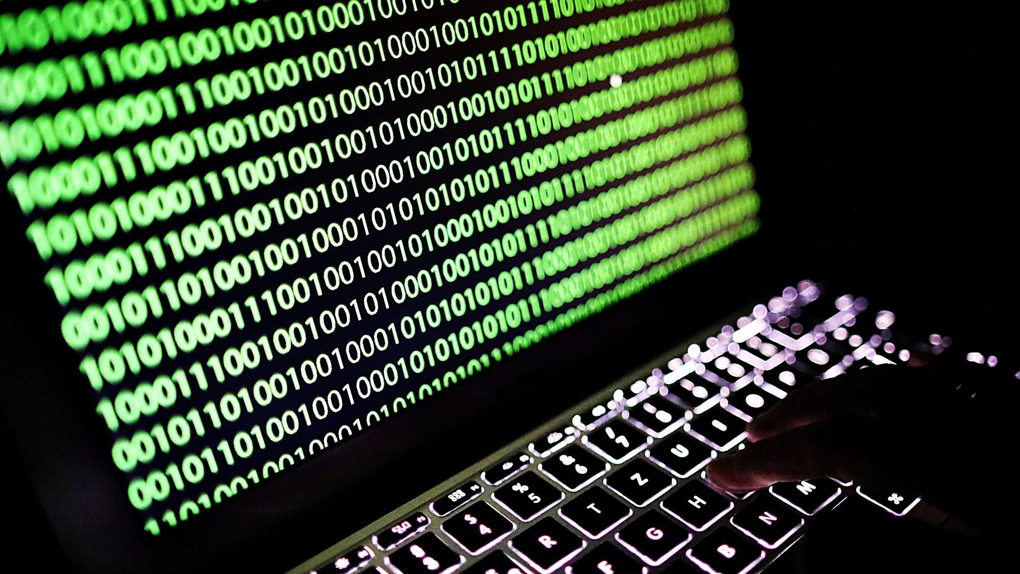 Auf dem Bildschirm eines Laptops ist ein Binärcode zu sehen.
