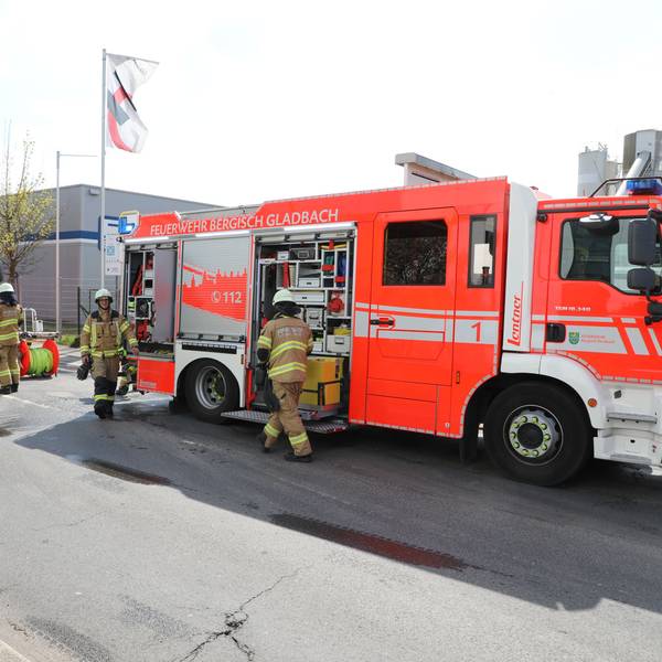 Feuerwehrfahrzeuge stehen auf einer gesperrten Straße. Feuerwehrleute laden Einsatzgerät aus.