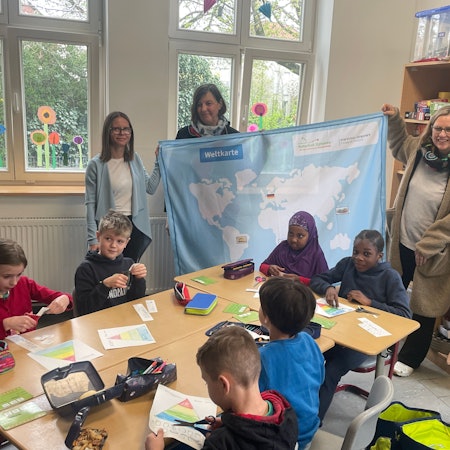Annette Beggerow (Stiftung Simon), Ursula Pauli (Ernährungsexpertin Naturgut Ophoven) und Ute Pfeiffer-Frohnert (Leiterin Kinder- und Jugendmuseum Energiestadt) vor Schülern der GGS Opladen.