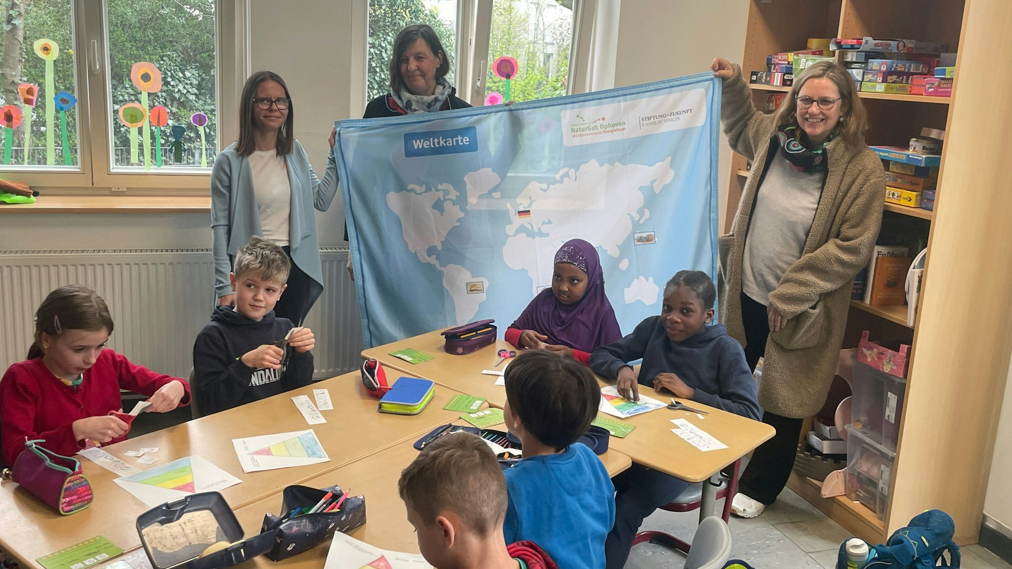 Annette Beggerow (Stiftung Simon), Ursula Pauli (Ernährungsexpertin Naturgut Ophoven) und Ute Pfeiffer-Frohnert (Leiterin Kinder- und Jugendmuseum Energiestadt) vor Schülern der GGS Opladen.