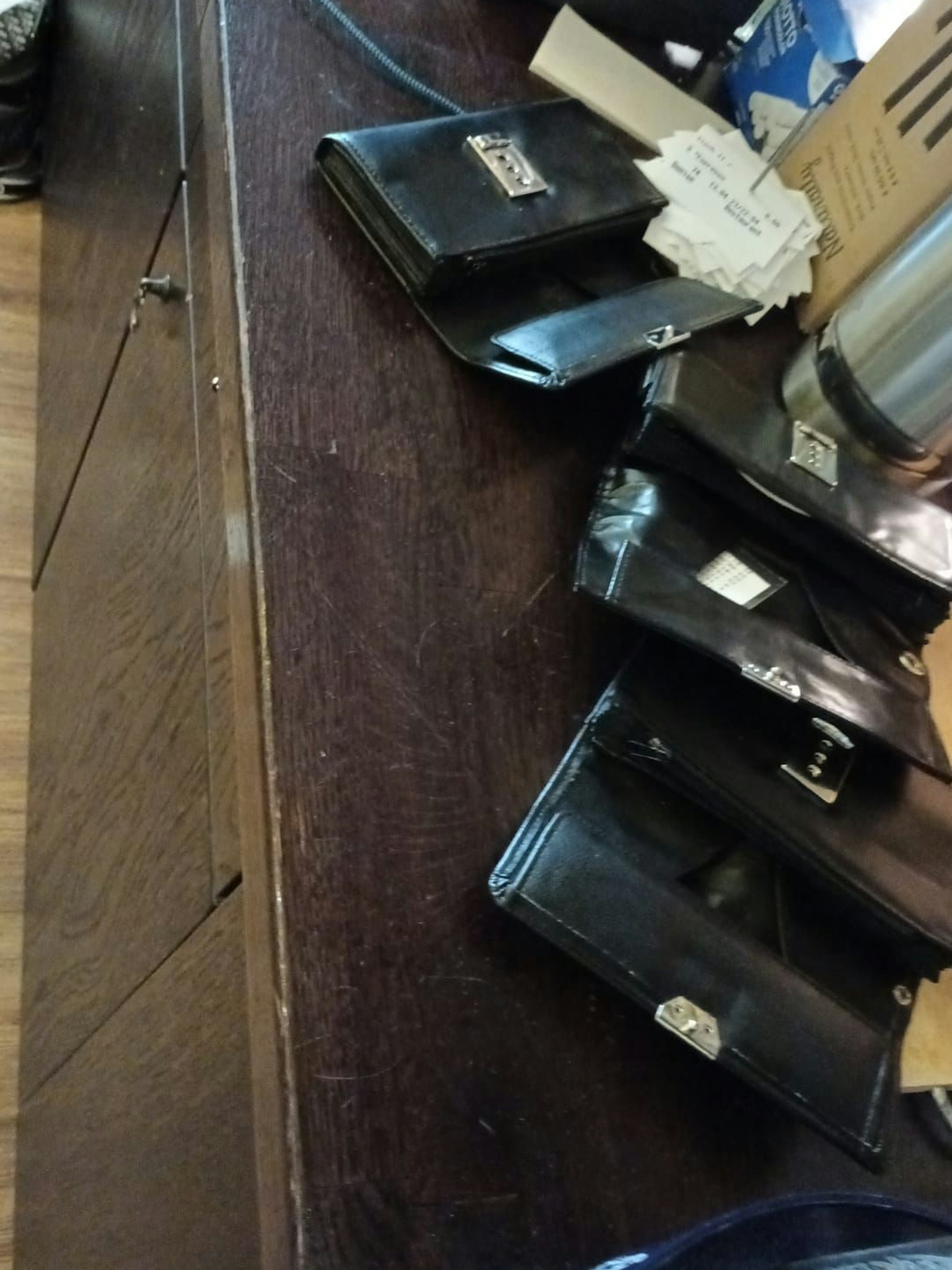 Mehrere Kellnerportemonnaies liegen leergeräumt auf einem Tresen.