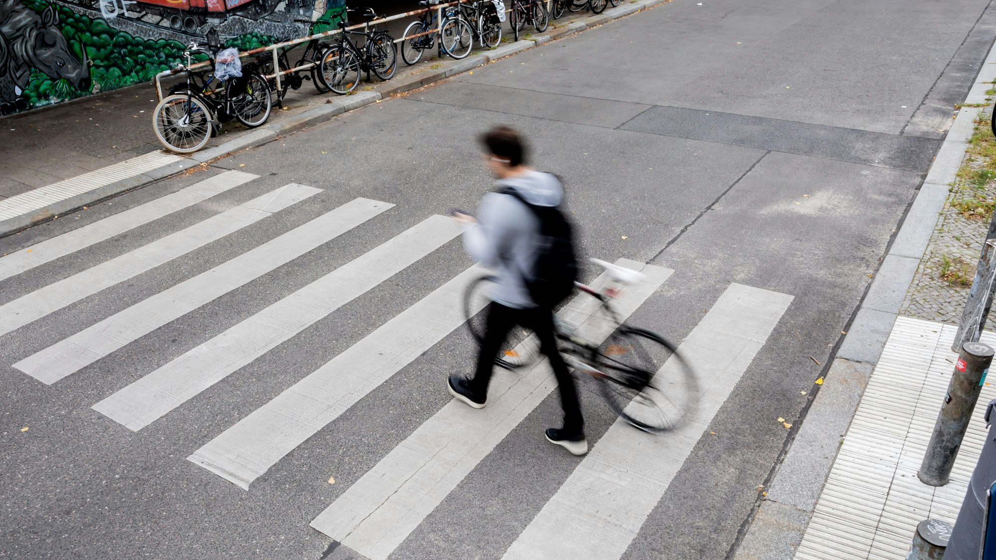 Ein Fahrradfahrer schiebt sein Fahrrad über einen Zebrastreifen.