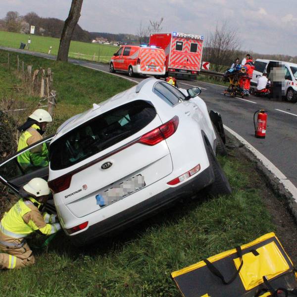 Schwer beschädigte Autos stehen neben einer Straße. Feuerwehrleute und Rettungsdienstmitarbeitende sind im Einsatz.