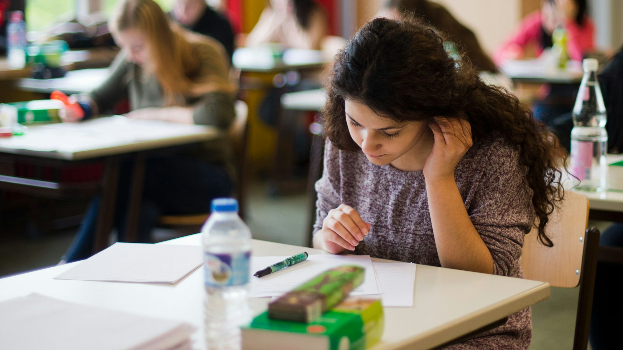 Eine Schülerin blickt bei der Abiturprüfung konzentriert auf ihre Aufgaben - seit 2007 gibt es eine stetige Zunahme besserer Abiturnoten.