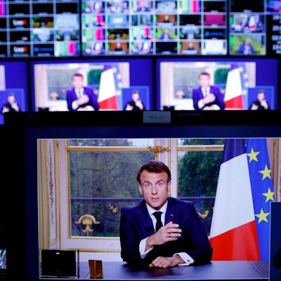 Ein Bild von Monitoren in einem Medienkontrollraum zeigt Emmanuel Macron, Präsident von Frankreich, während einer im Fernsehen übertragenen Ansprache an die Nation.