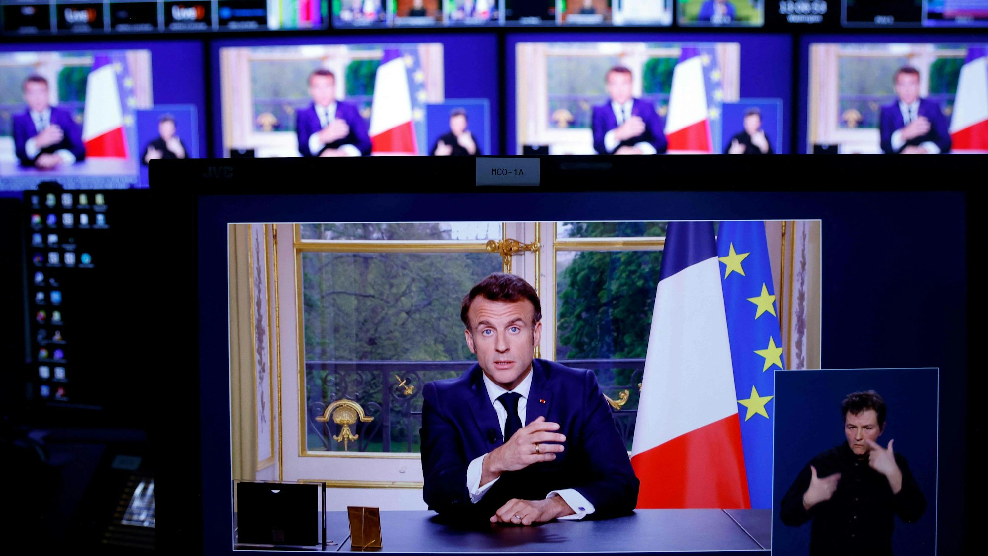 Ein Bild von Monitoren in einem Medienkontrollraum zeigt Emmanuel Macron, Präsident von Frankreich, während einer im Fernsehen übertragenen Ansprache an die Nation.