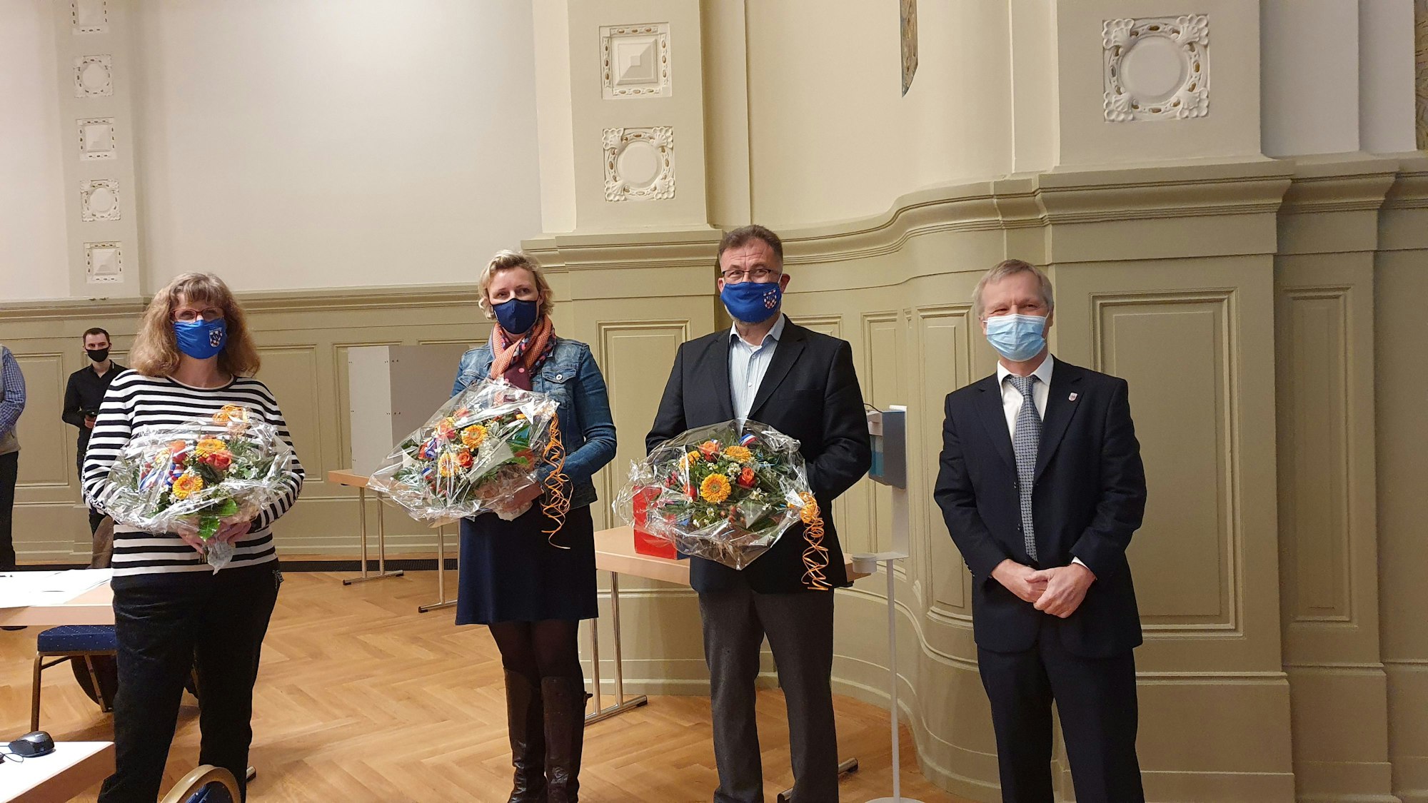 Zwei Frauen und zwei Männer – wegen Corona alle mit blauem Mundnasenschutz – stehen nebeneinander im Kurssaal. Die drei gerade gewählten Vize-Bürgermeister halten Blumensträuße in den Händen.