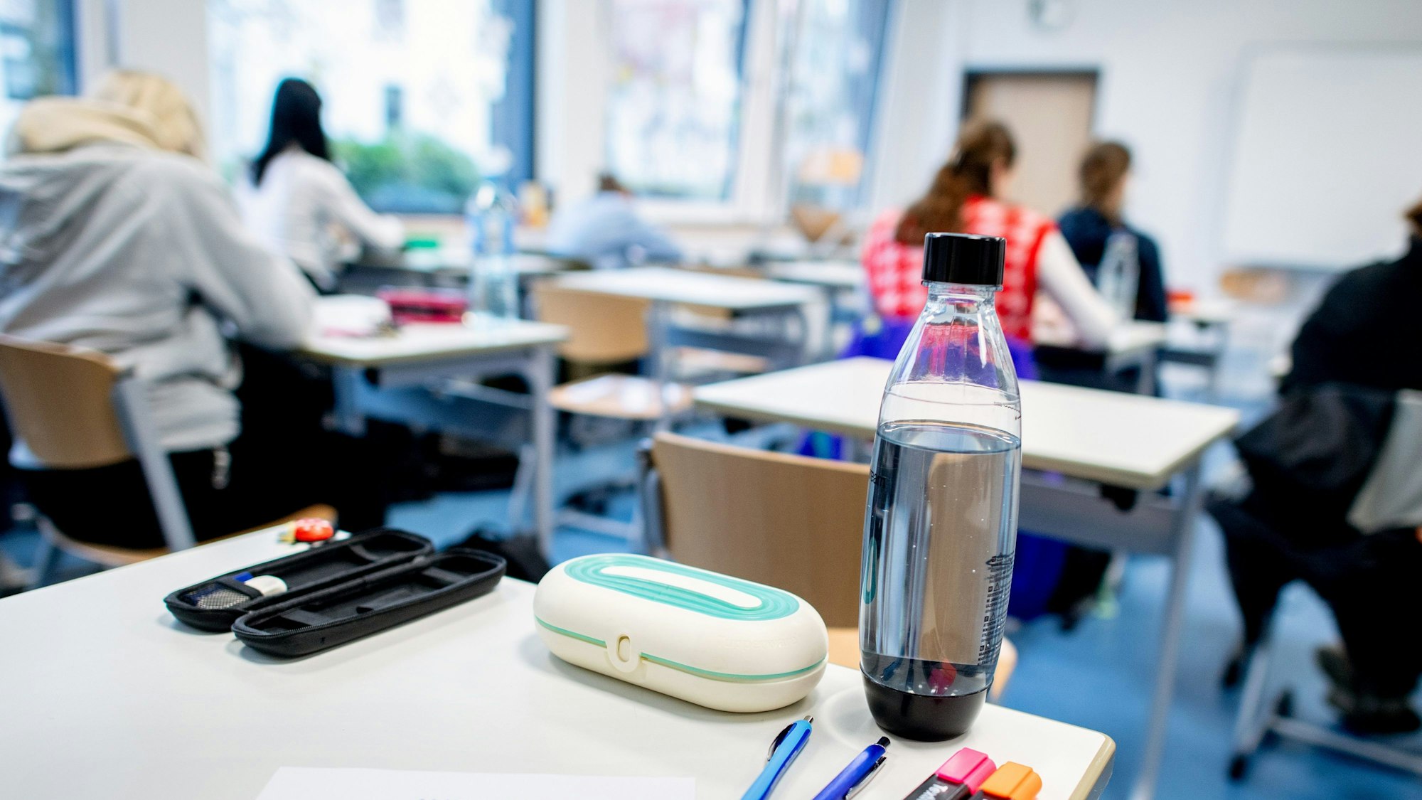 Mehrere Stifte liegen und eine Wasserflasche steht vor Beginn der schriftlichen Prüfungen auf dem Tisch.