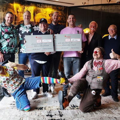 Die Sportlegenden Stefan Blank, Christian Ramota, Pascal Hens und Stefan Kretzschmar überreichen einen symbolischen Scheck in Höhe von 12.000 Euro an wir helfen und 13.400 Euro an den Kölner Verein Kindernöte e.V. Mit im Bild sind die beiden Klinikclowns Hallihallo und Lupo.