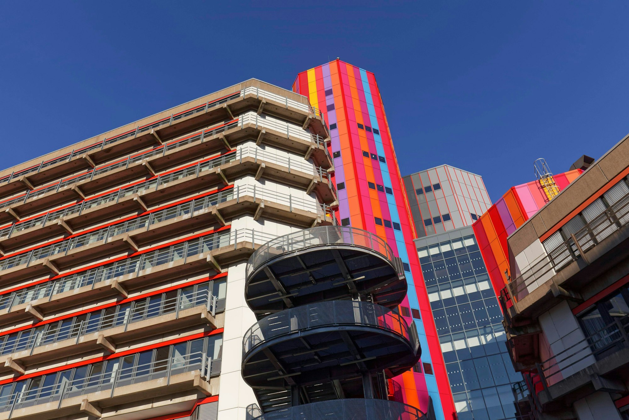 Ein Gebäude der Universität Duisburg-Essen auf dem Campus Essen ist zu sehen. Ein funktioneller Hochhausbau mit rotem Treppenturm.