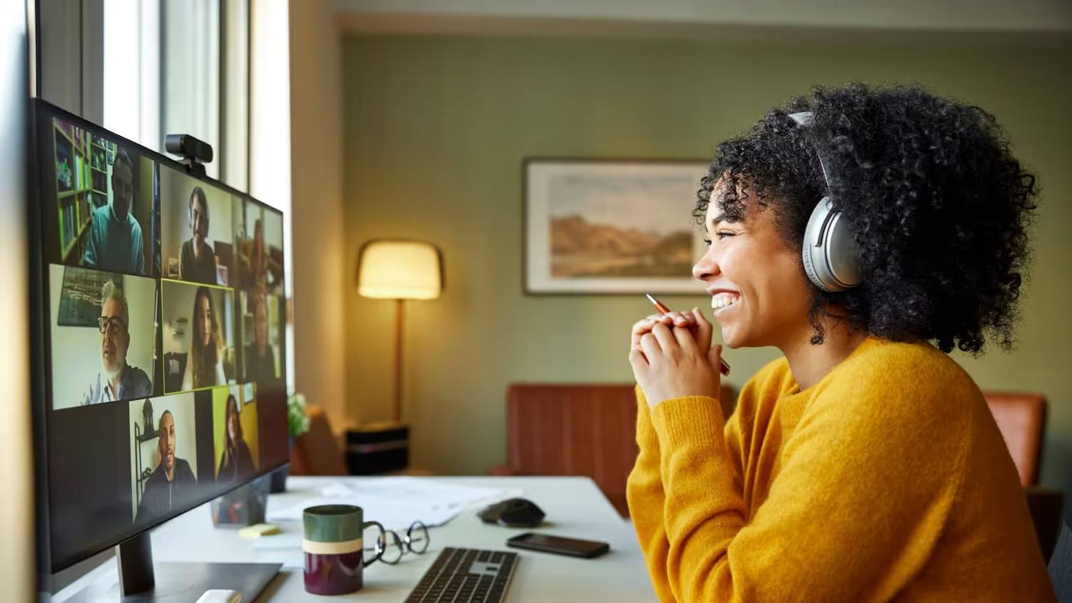 Businesswoman with headphones smiling during video conference. Multiracial male and female professionals are attending online meeting. They are discussing business strategy.