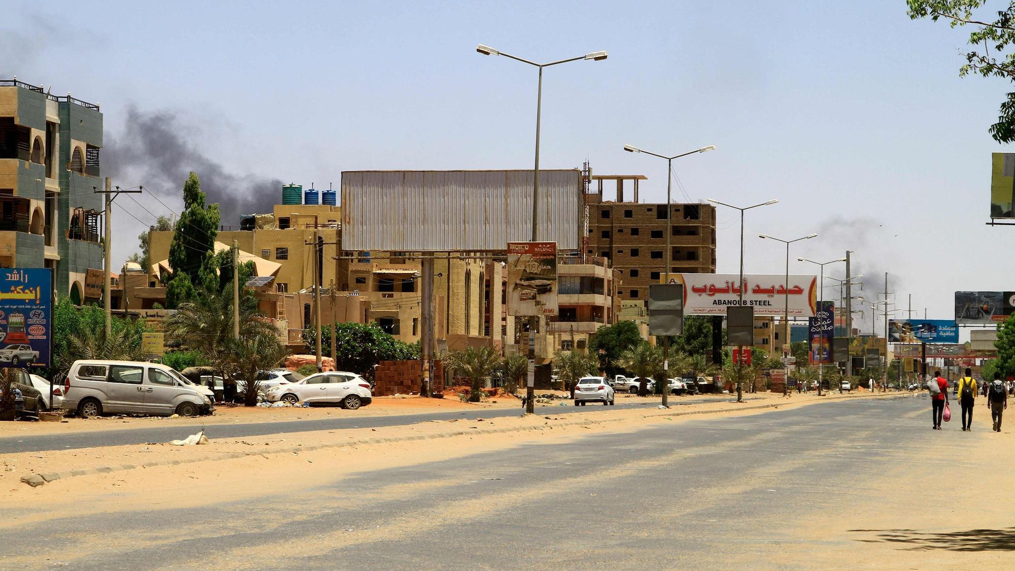 Straße im Sudan, am Himmel ist Rauch zu sehen.