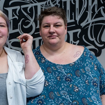 Antonia und Heidi Hartrumpf zeigen ihr Organspendetattoo, das zwei Halbkreise und einen Kreis zeigt.